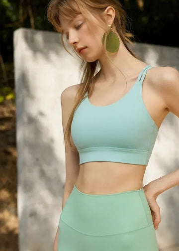 Woman wearing a light green sports bra and leggings outdoors.